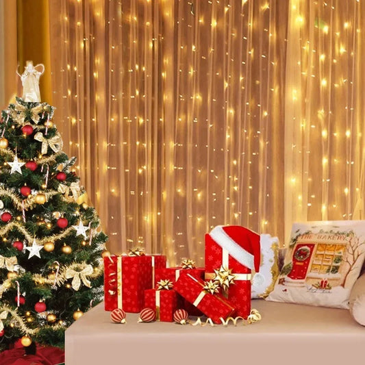 Decorated Christmas tree with presents and a Santa hat in front of a curtain with string lights.