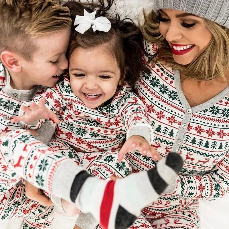 Family wearing matching holiday-themed pajamas with a woman and two children.