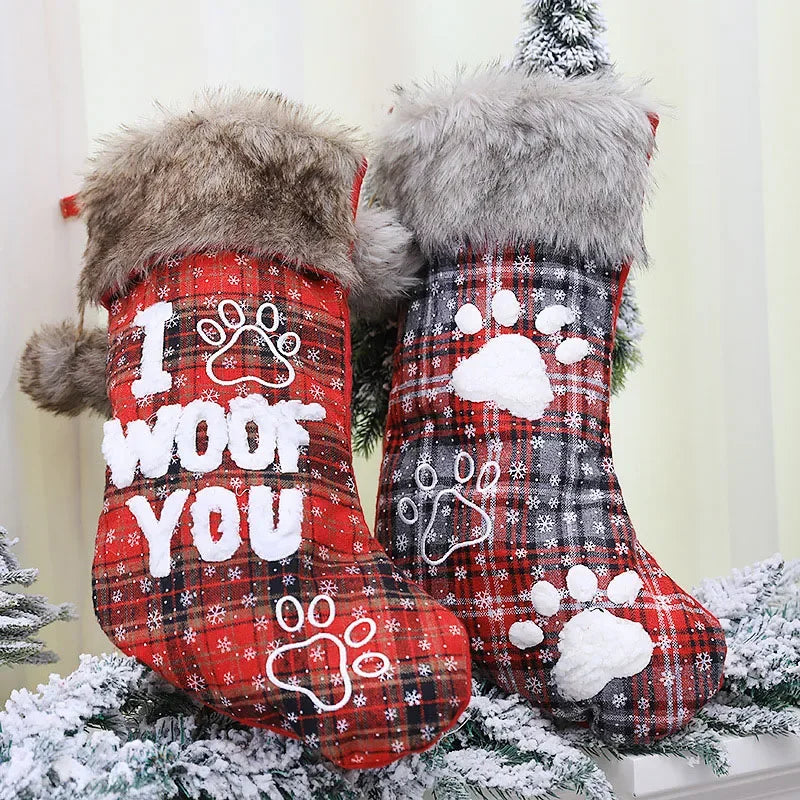 Two red plaid Christmas stockings with paw prints and text on a snowy background