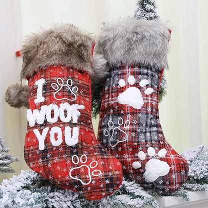 Two red plaid Christmas stockings with paw prints and text on a snowy background