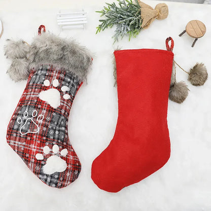Two Christmas stockings, one plaid with paw prints and one red, on a white background.