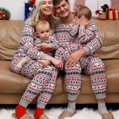 Family of four wearing matching holiday pajamas sitting on a couch.