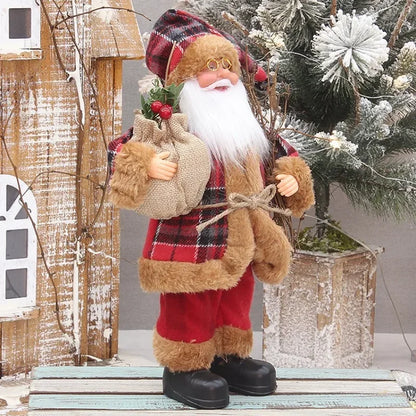 Decorative Santa Claus figure with a plaid hat and red outfit, standing in front of a Christmas tree.
